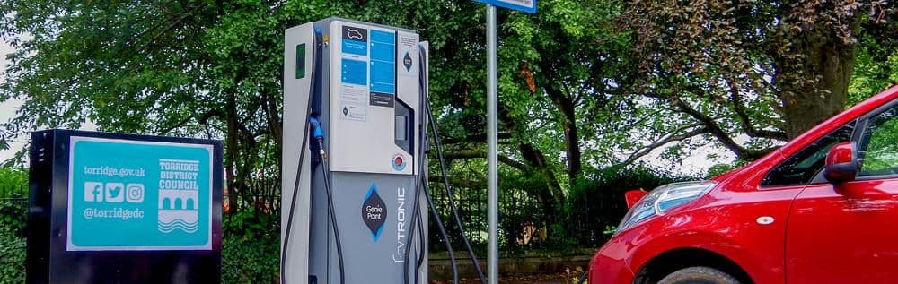 A public car charging point surrounded by trees