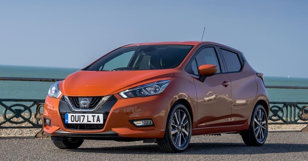 Orange Nissan Micra 2017 parked by a seaside railing, under a clear blue sky