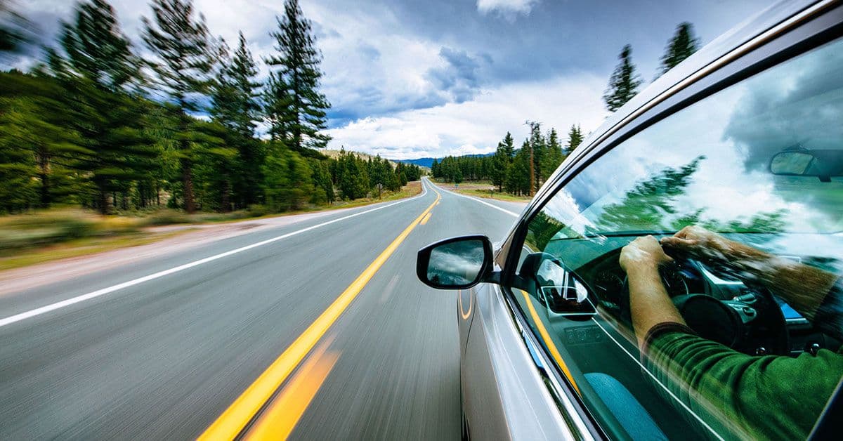Ein Elektroauto fährt schnell eine Straße mit Bäumen entlang