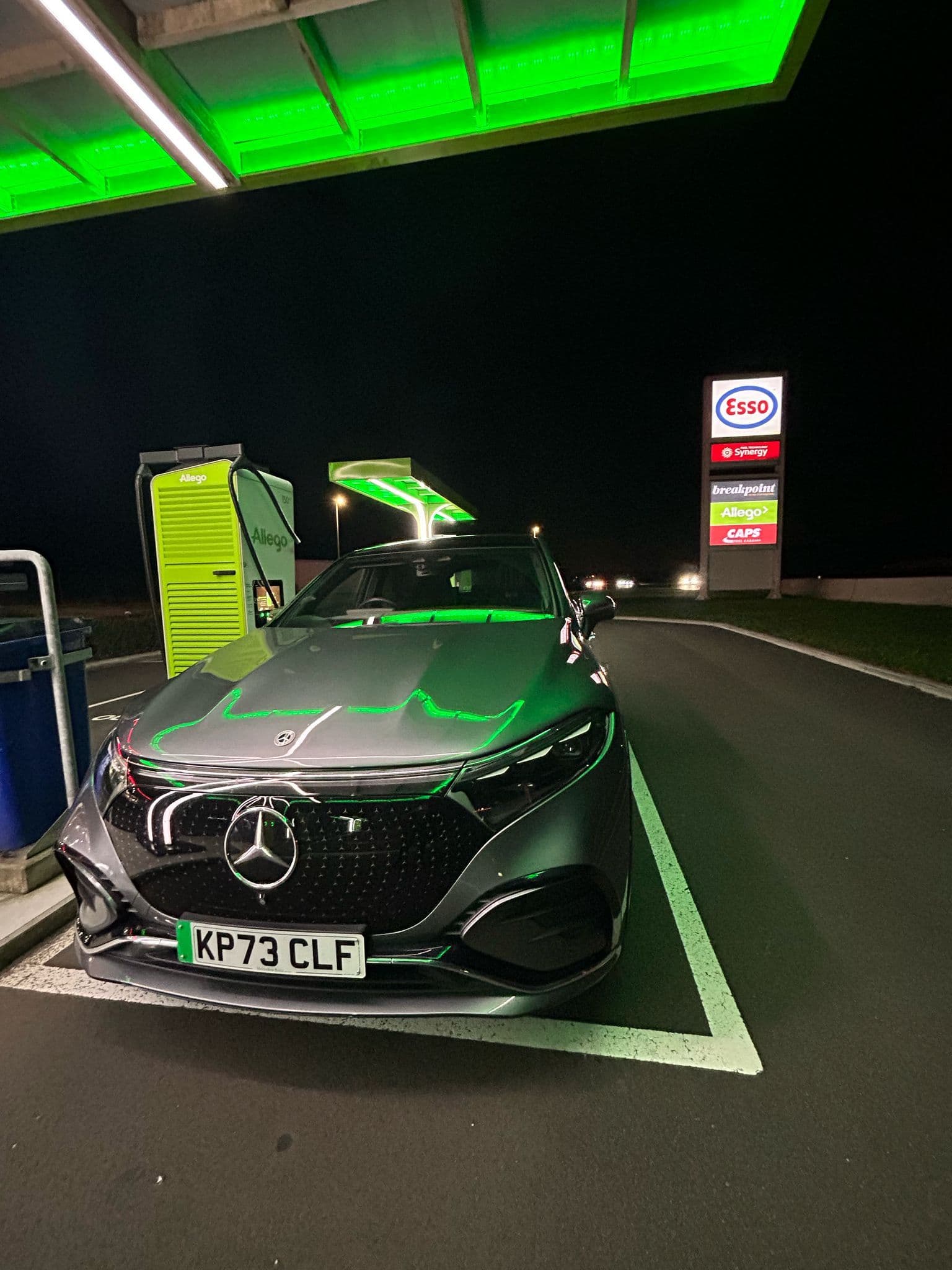 Mercedes at EV charger under green light. Mercedes en el cargador de vehículos eléctricos con luz verde. Mercedes alla stazione di ricarica per veicoli elettrici con luce verde. Mercedes em carregador de veículos elétricos sob luz verde. Mercedes an der Ladestation für Elektrofahrzeuge mit grünem Licht. Mercedes au chargeur EV sous le feu vert.