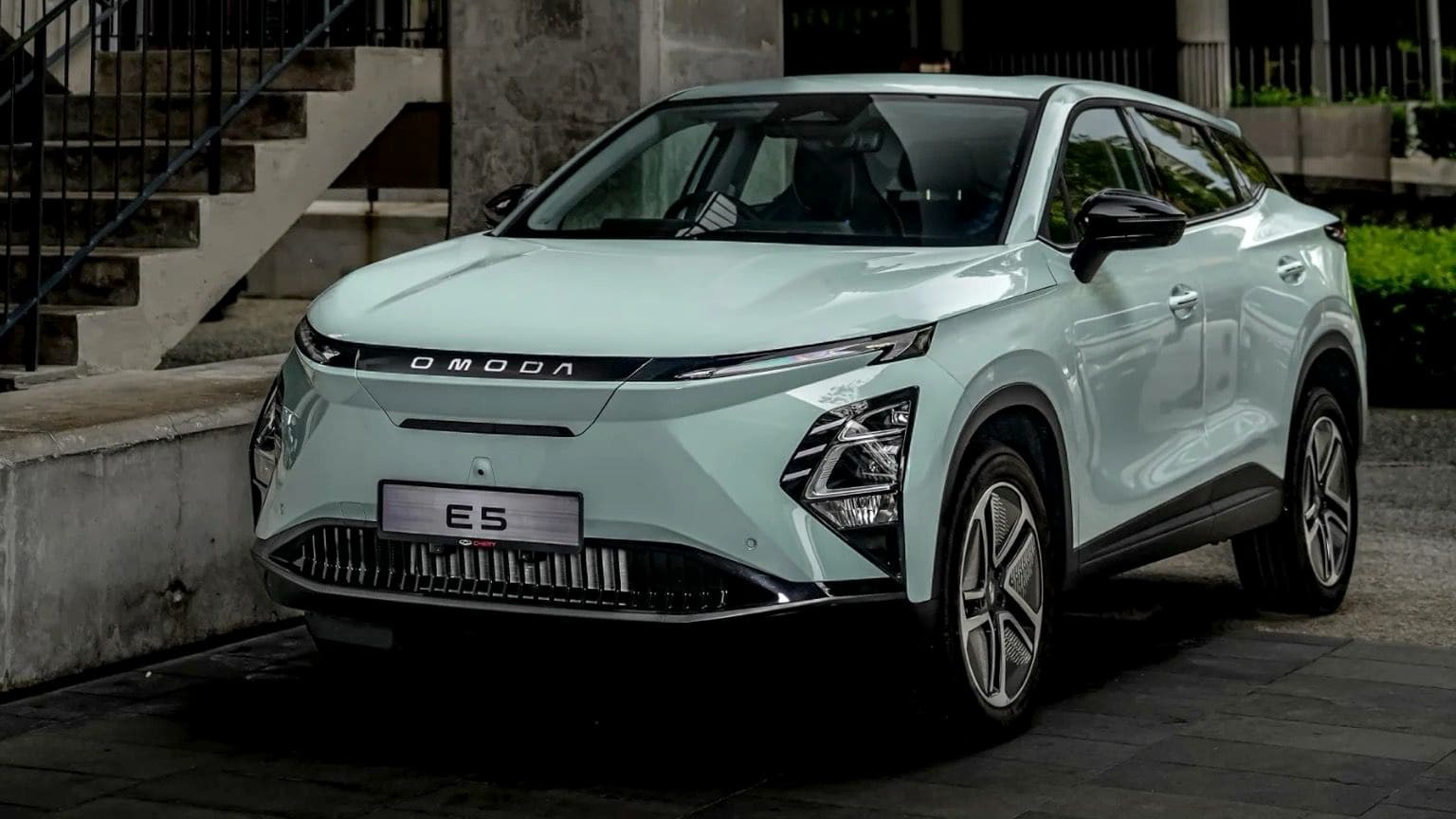 Un elegante y moderno SUV azul claro aparcado en un entorno urbano, con faros afilados y una parrilla distintiva.