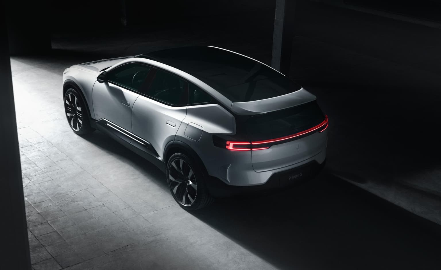 Un veicolo SUV elettrico Polestar 3 di colore argento, che attraversa una strada di cemento buia