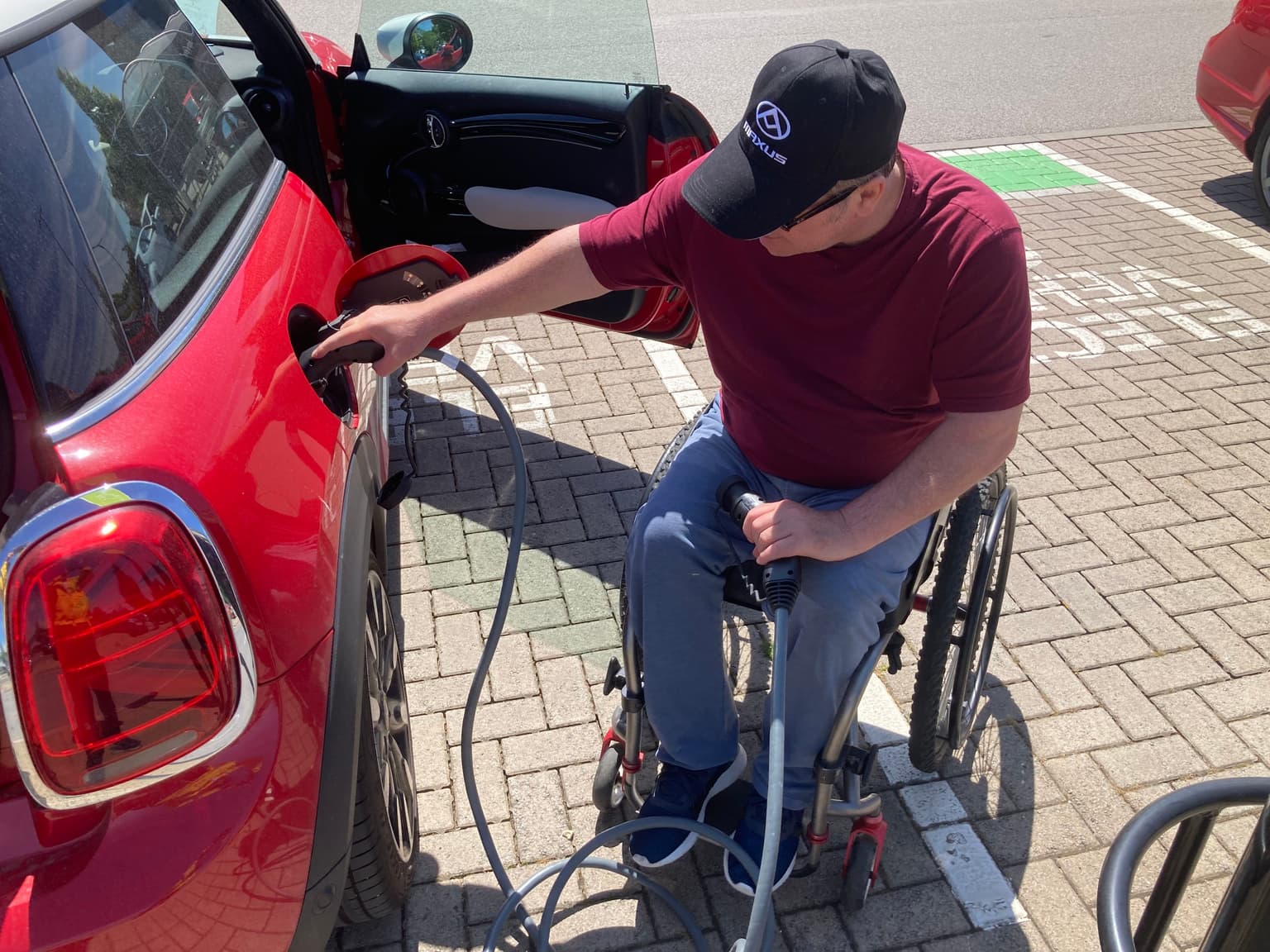 photo of man, roger warner, charging EV while in wheelchair