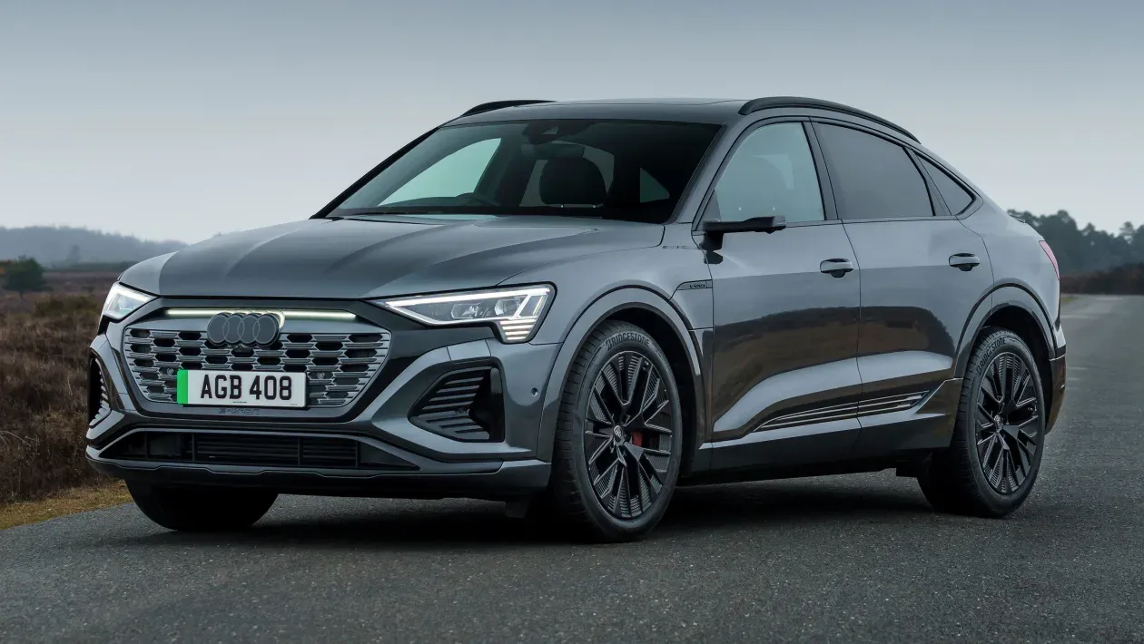 Elegante SUV Audi Q8 Sportback gris estacionado en una carretera, con un diseño moderno con faros LED distintivos y elegantes llantas de aleación.