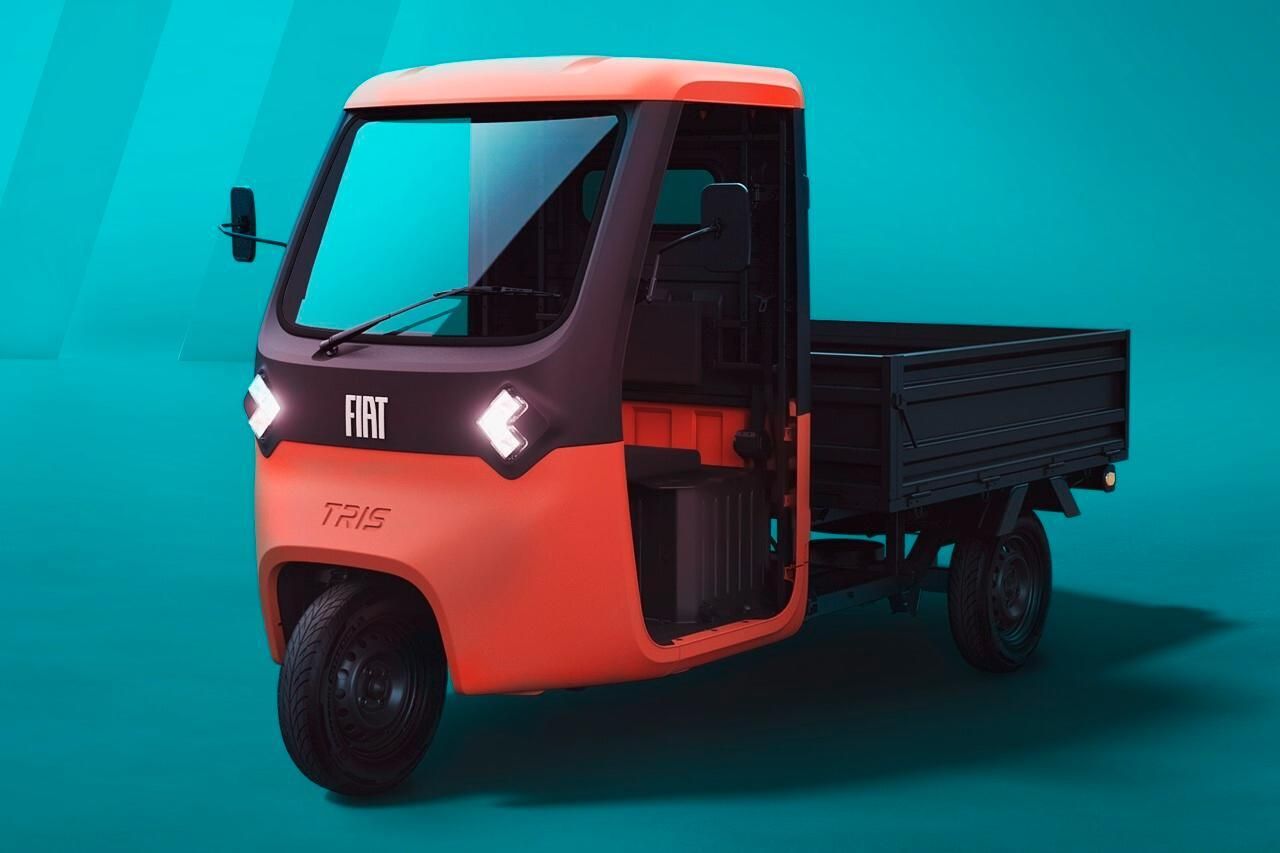 Bright orange Fiat Tris three-wheeled utility vehicle with an open cargo bed against a blue background.