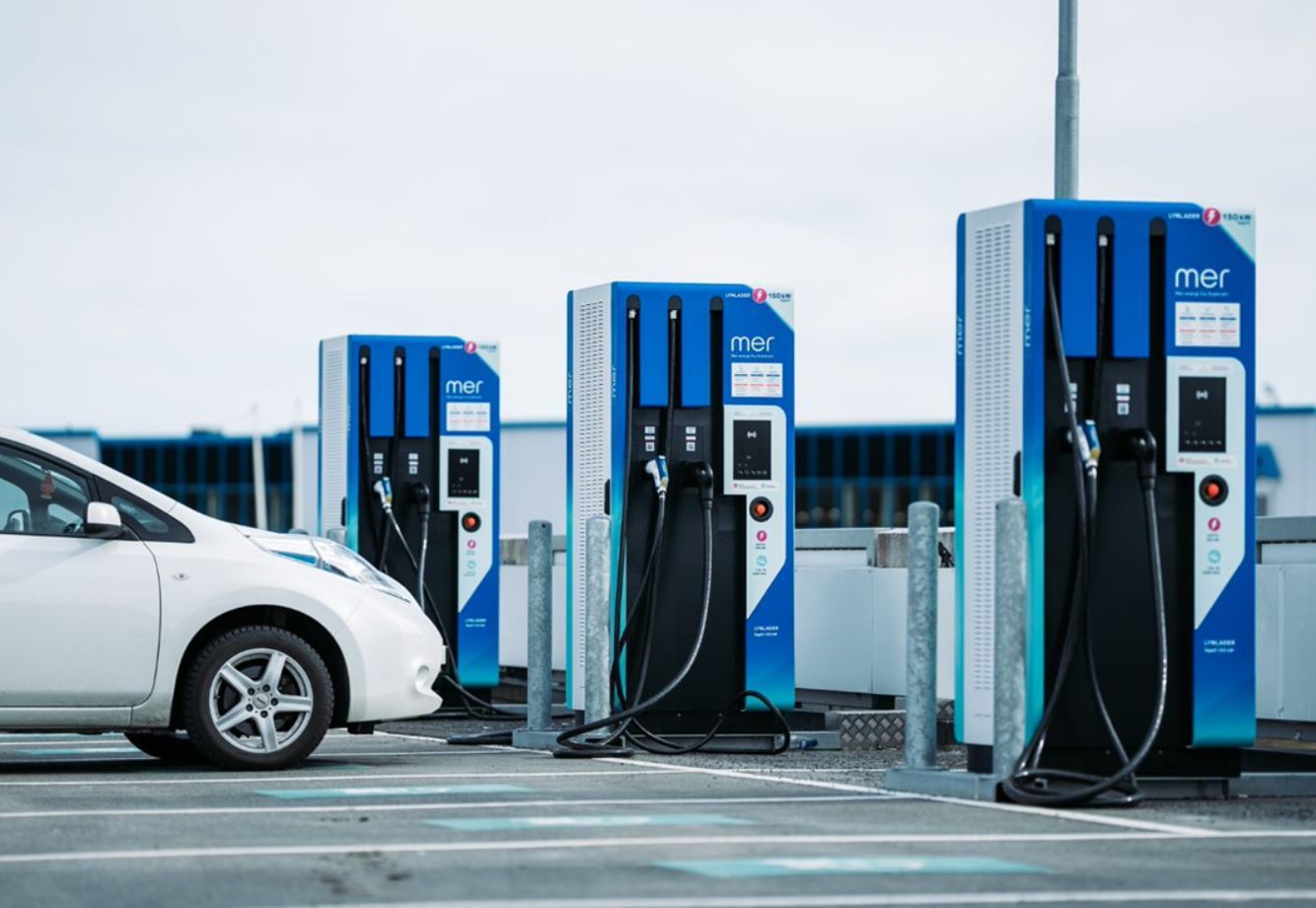 A mer germany charging station. Elektroauto, das an einer Ladestation mit drei blauen MER-Ladeeinheiten auf einem Außenparkplatz geparkt ist.