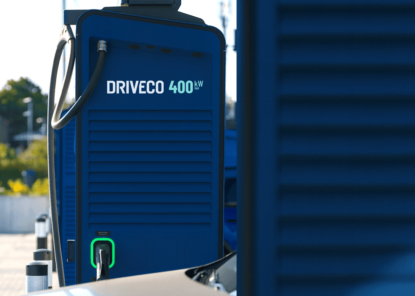 Blue DRIVECO 400 kW electric vehicle charging station with cable plugged into a car and a green-lit connector.