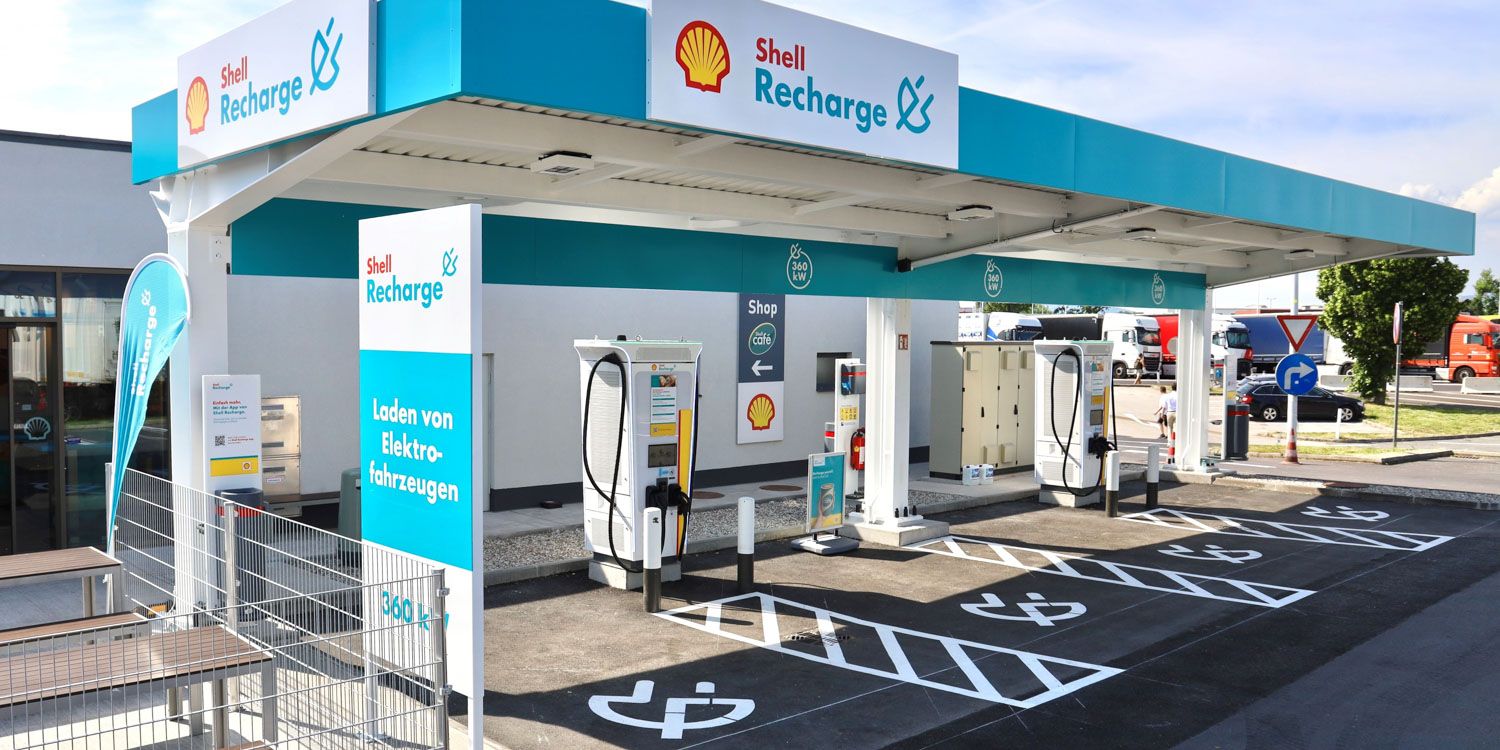 Shell Recharge-Ladestation für Elektrofahrzeuge mit mehreren Ladeeinheiten und Parkplätzen unter einem Dach, mit Shell-Branding.