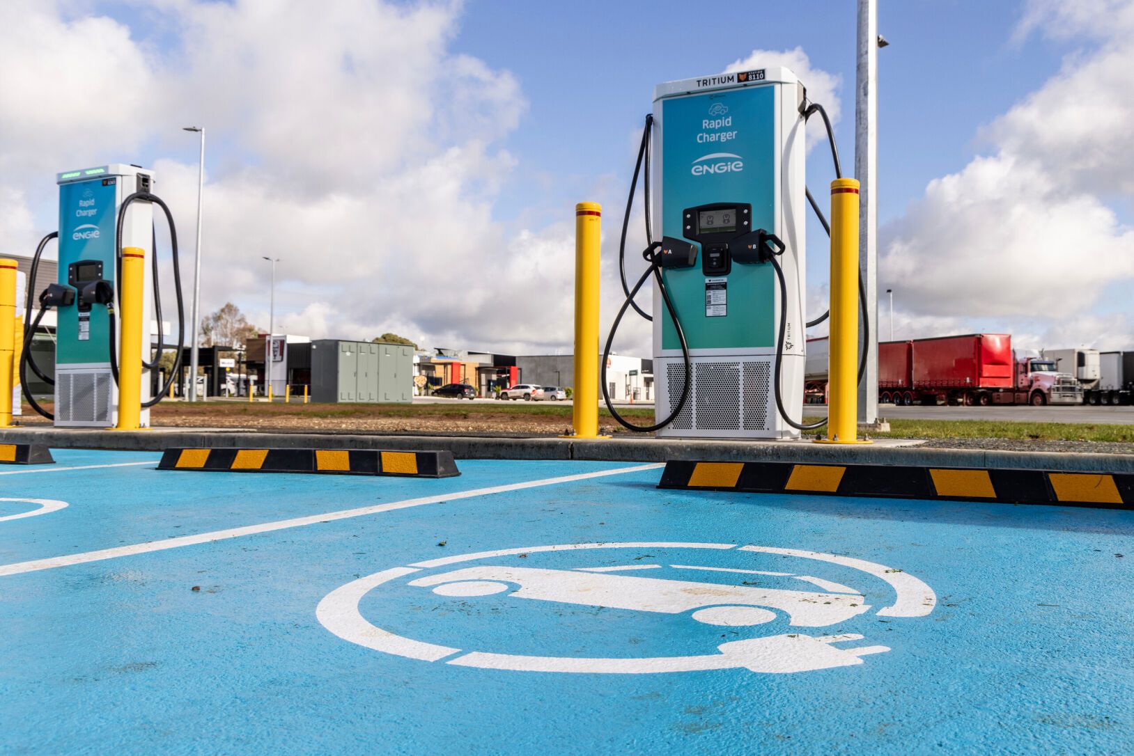 Station de recharge pour véhicules électriques avec plusieurs bornes Engie Vianeo et places de stationnement délimitées, sur fond de ciel nuageux.