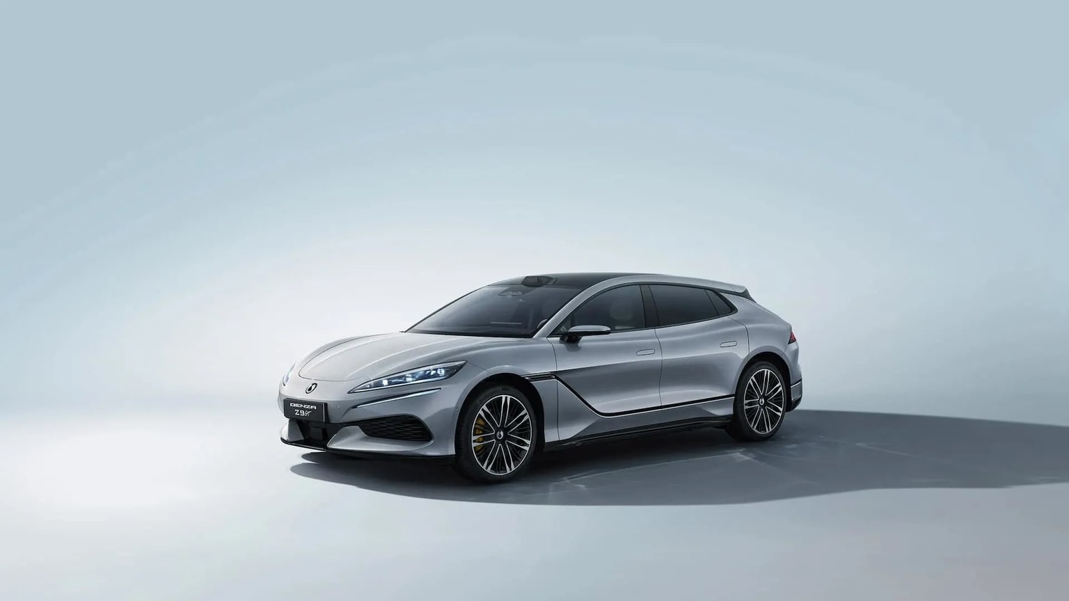 Sleek silver BYD Denza sedan with tinted windows and elegant design, set against a light, neutral background.