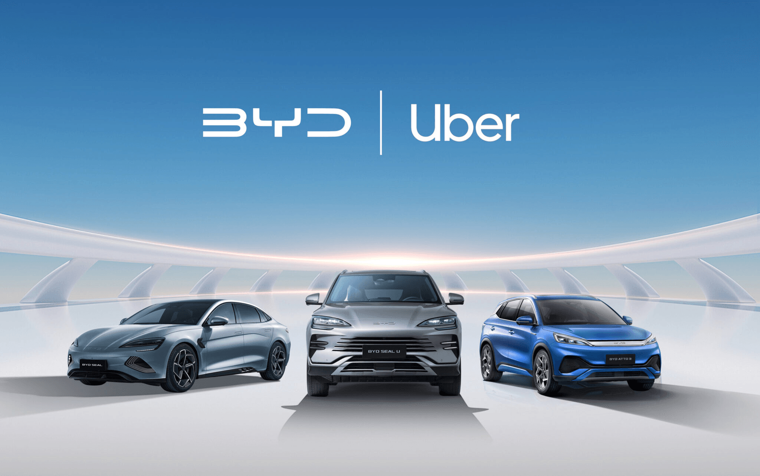Tre auto BYD esposte sotto un cielo azzurro e terso, con la scritta "BYD | Uber" sopra, a dimostrazione di una partnership.