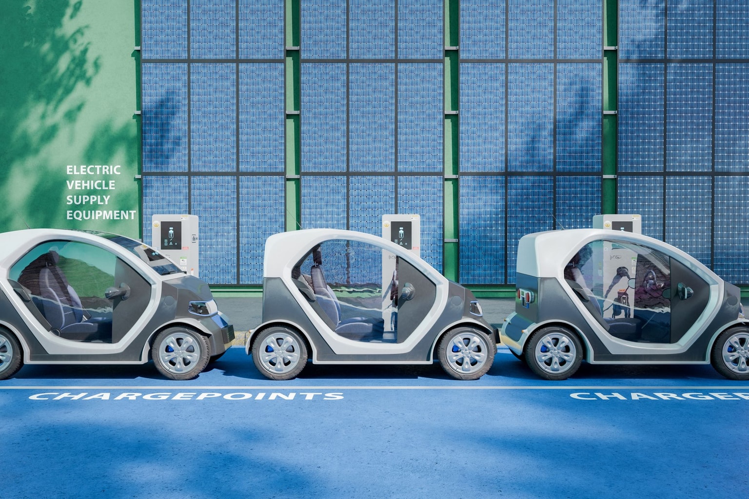 Three small electric vehicles parked at charging stations against a green building with large solar panels.