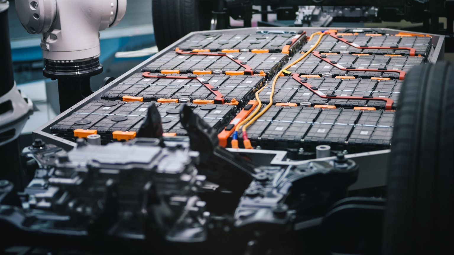 Close-up of an electric vehicle battery pack with visible connections and cables, placed in a car chassis.