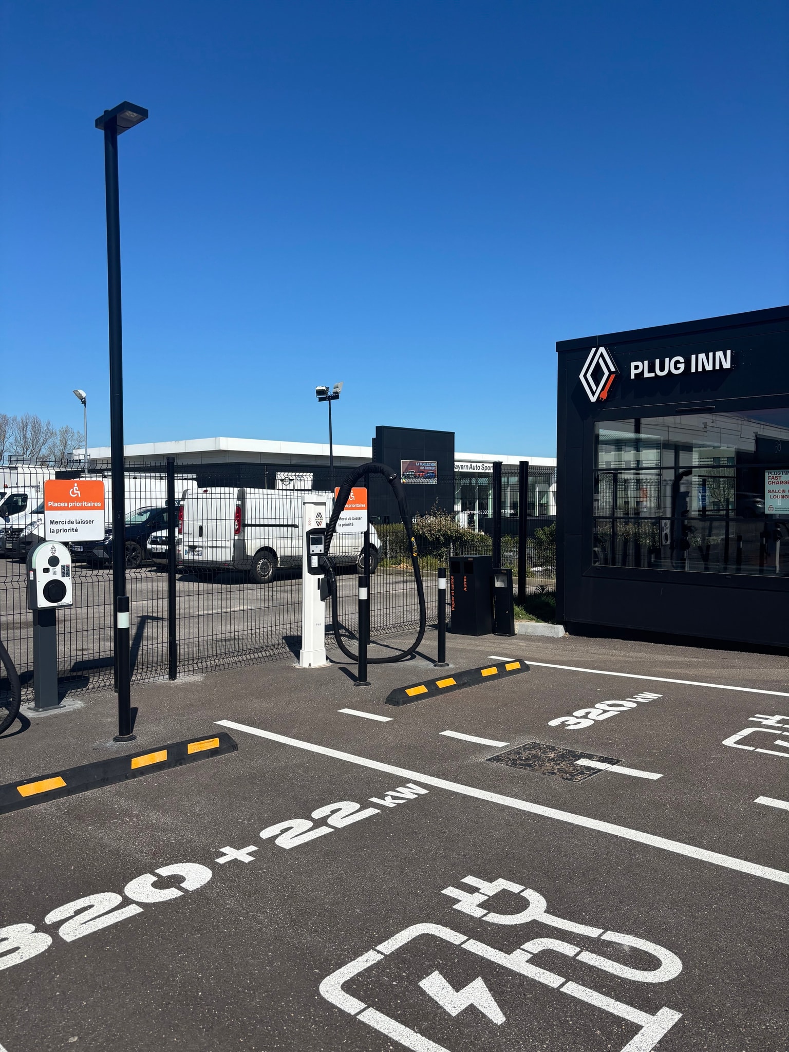 Plug Inn electric vehicle charging station with multiple plugs, parking spots, and clear signage on a sunny day.