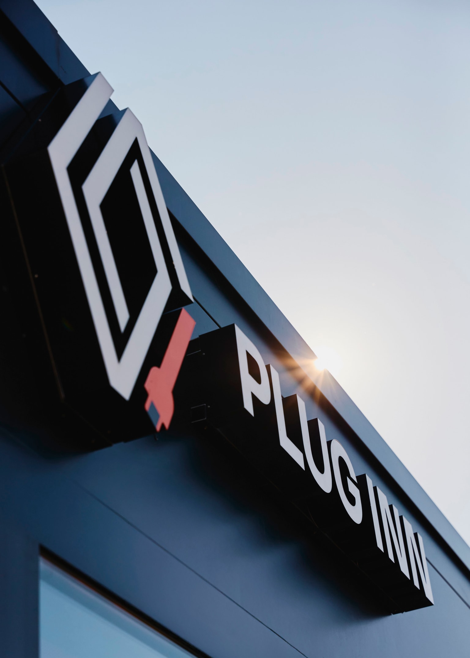 A zoomed in photo of a building with the words "Plug Inn" in letters sticking out of the wall. The Renault and Plug Inn logo is next to it in 3D.