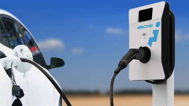 Electric car charging at a station labeled "electrip" under a clear blue sky.