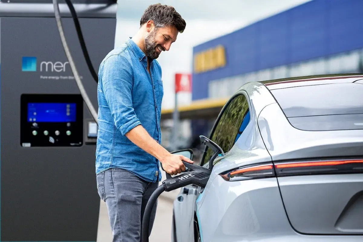 Man charging EV at MER station. Mann lädt Elektrofahrzeug an MER-Tankstelle auf