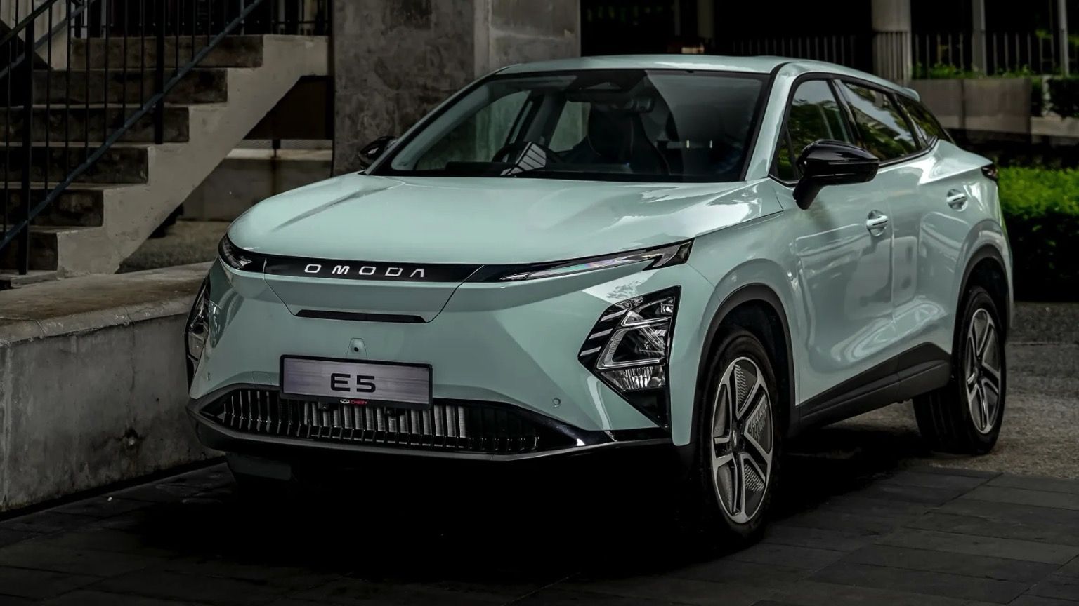 Un elegante y moderno SUV azul claro aparcado en un entorno urbano, con faros afilados y una parrilla distintiva.