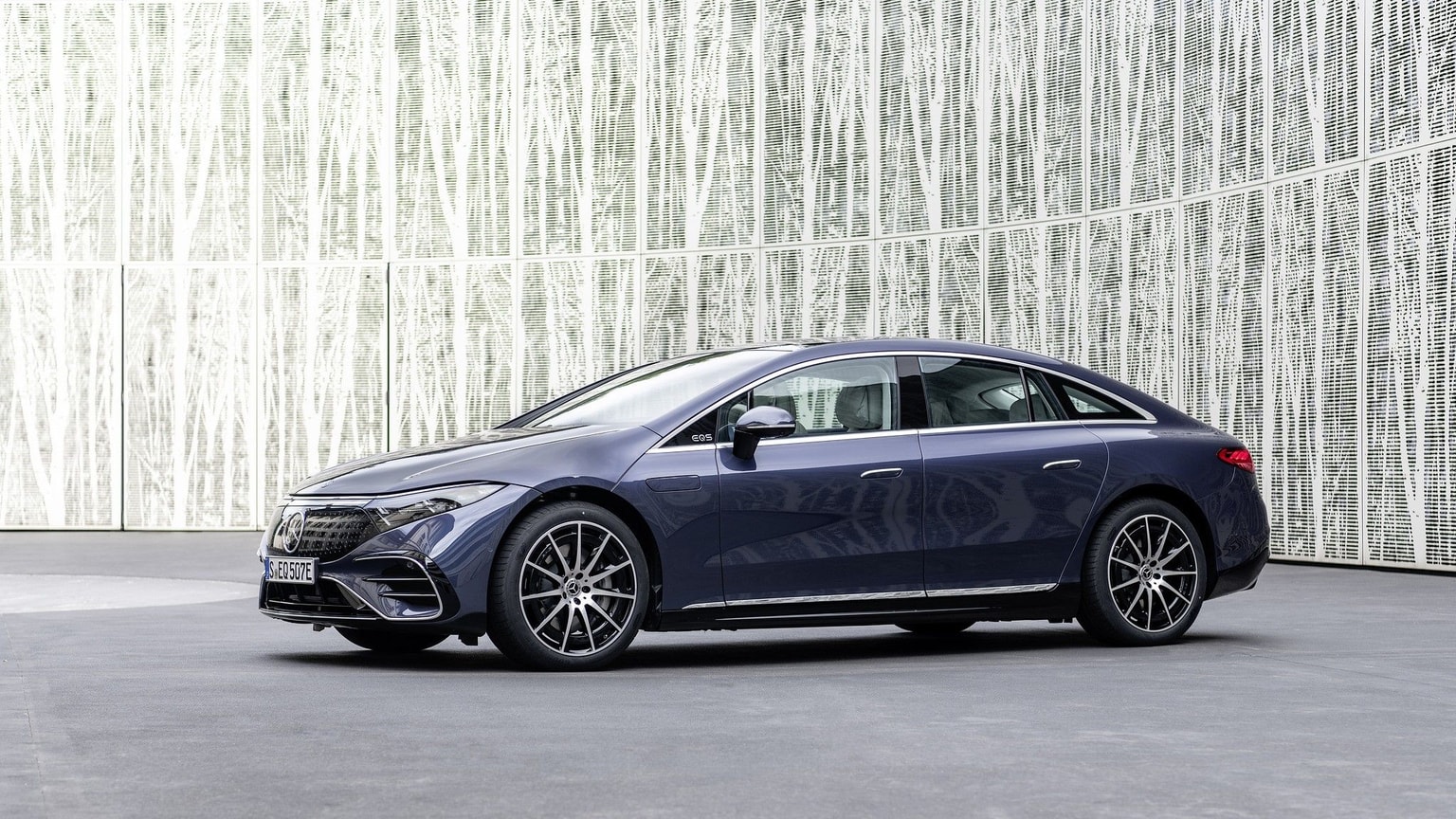 Carro azul-marinho numa plataforma de betão cinzenta com um fundo branco semelhante a uma árvore