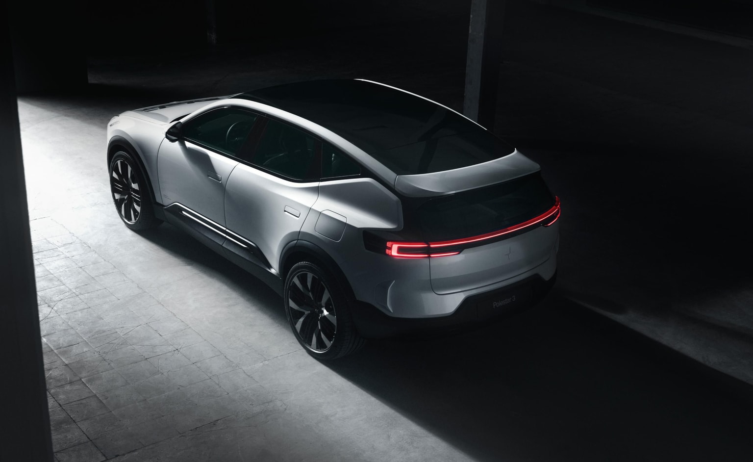 Un veicolo SUV elettrico Polestar 3 di colore argento, che attraversa una strada di cemento buia