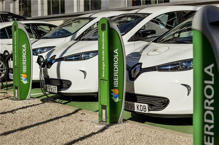 Voitures électriques blanches en charge dans les stations Iberdrola dans une zone de stationnement, avec une marque verte et un temps clair.