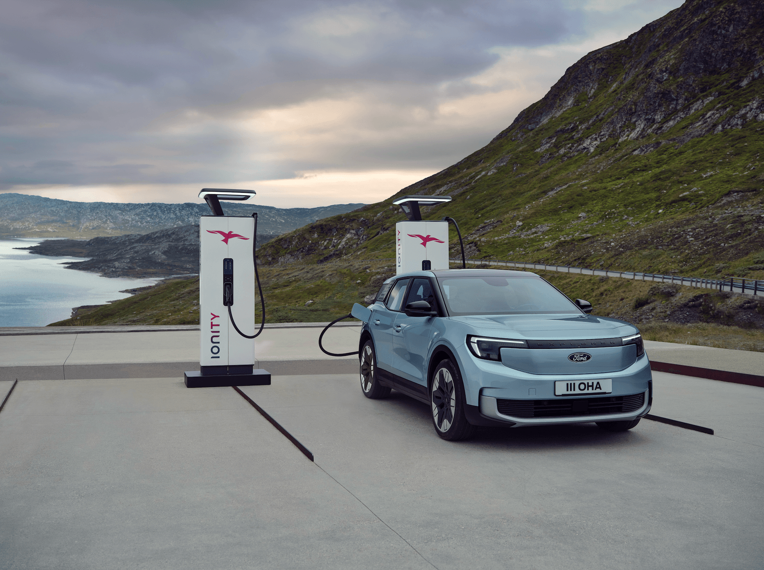 Blue electric ford explorer charging with an IONITY charging station, set against a mountain and lake background