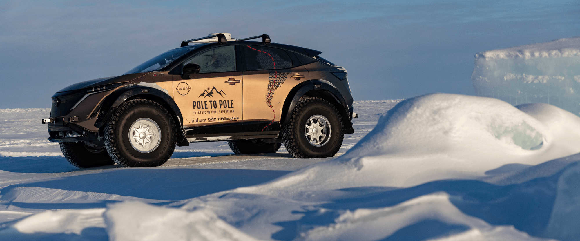 A customized electric vehicle with large tires is parked on a snowy landscape, featuring a "Pole to Pole" expedition logo on its side.
